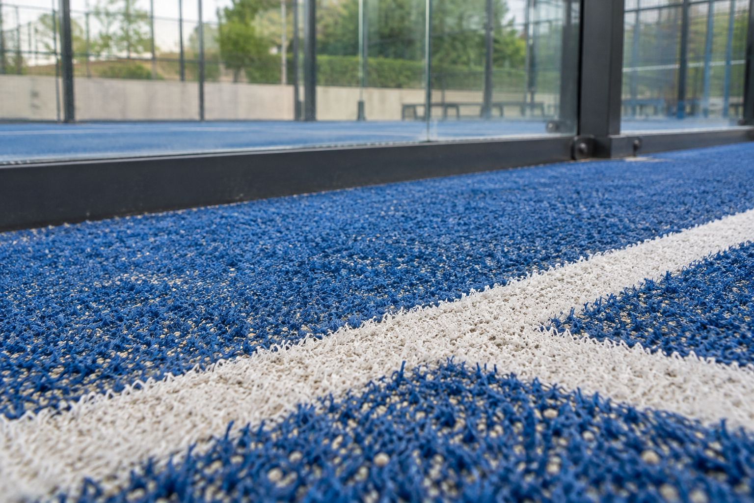 Illustrative blue padel turf fibres, white playing line and sand infill